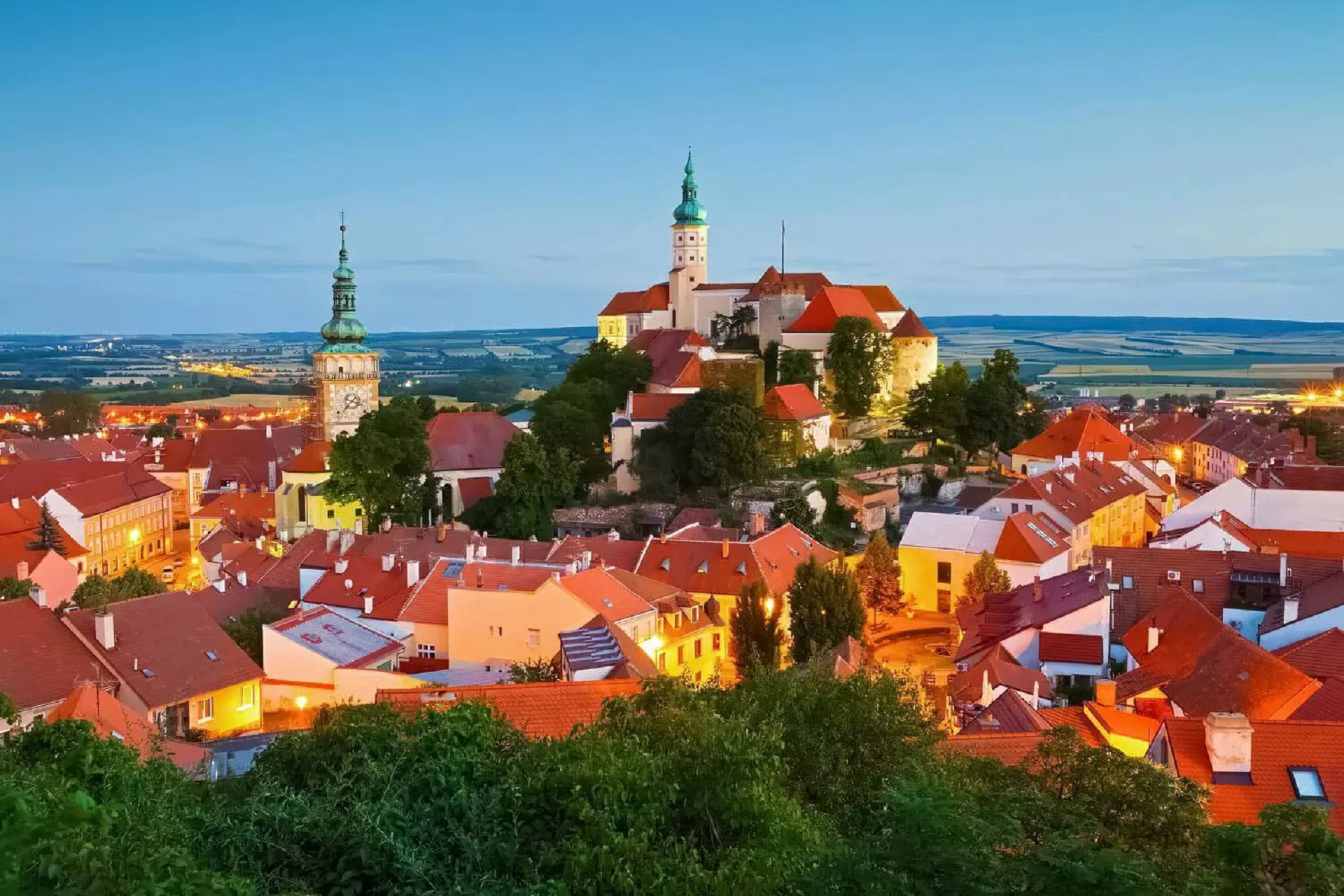 Vista parcial da cidade de MMikulov, na República Tcheca. Raios de Sol iluminam o casaredo. No horizonte se destaca uma torre.