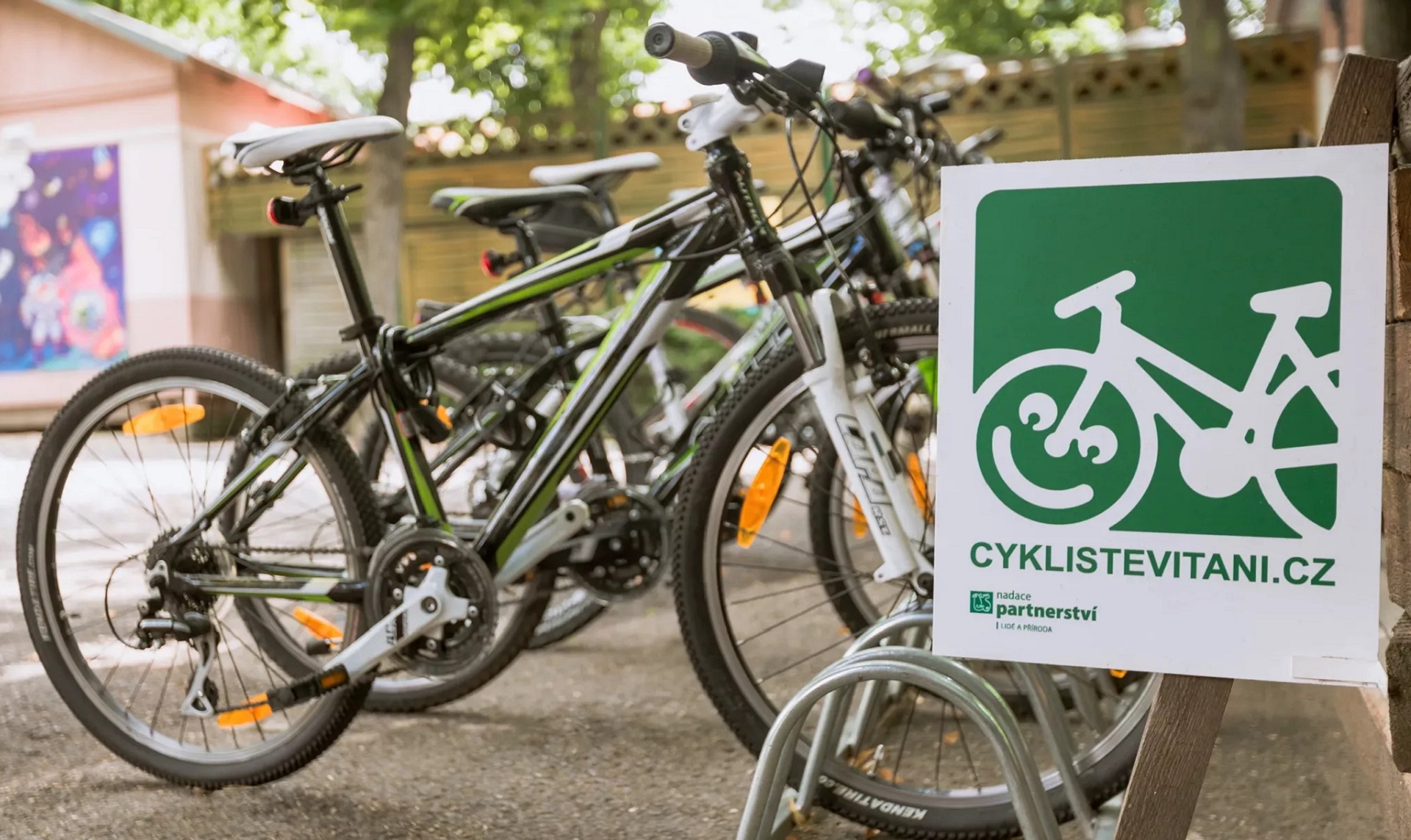 Bicicletas estacionadas junto a uma placa onde está estampada uma bicicleta estilizada, com o aro do pneu dianteiro está substituído por uma carinha sorridente.